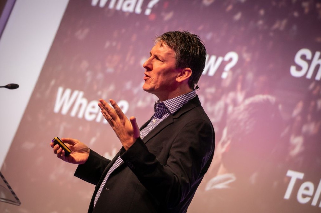Steve McNicholas gesturing during a keynote